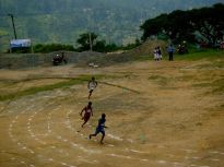 Children and young men and women running without shoes at a local track meet. Haputale, Sri Lanka